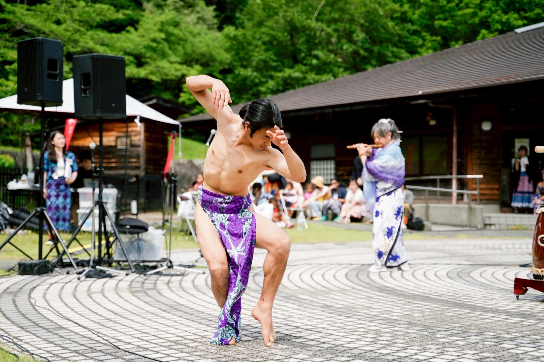 緑のなかの屋外舞台で四股舞をするMIKAGE 三影
