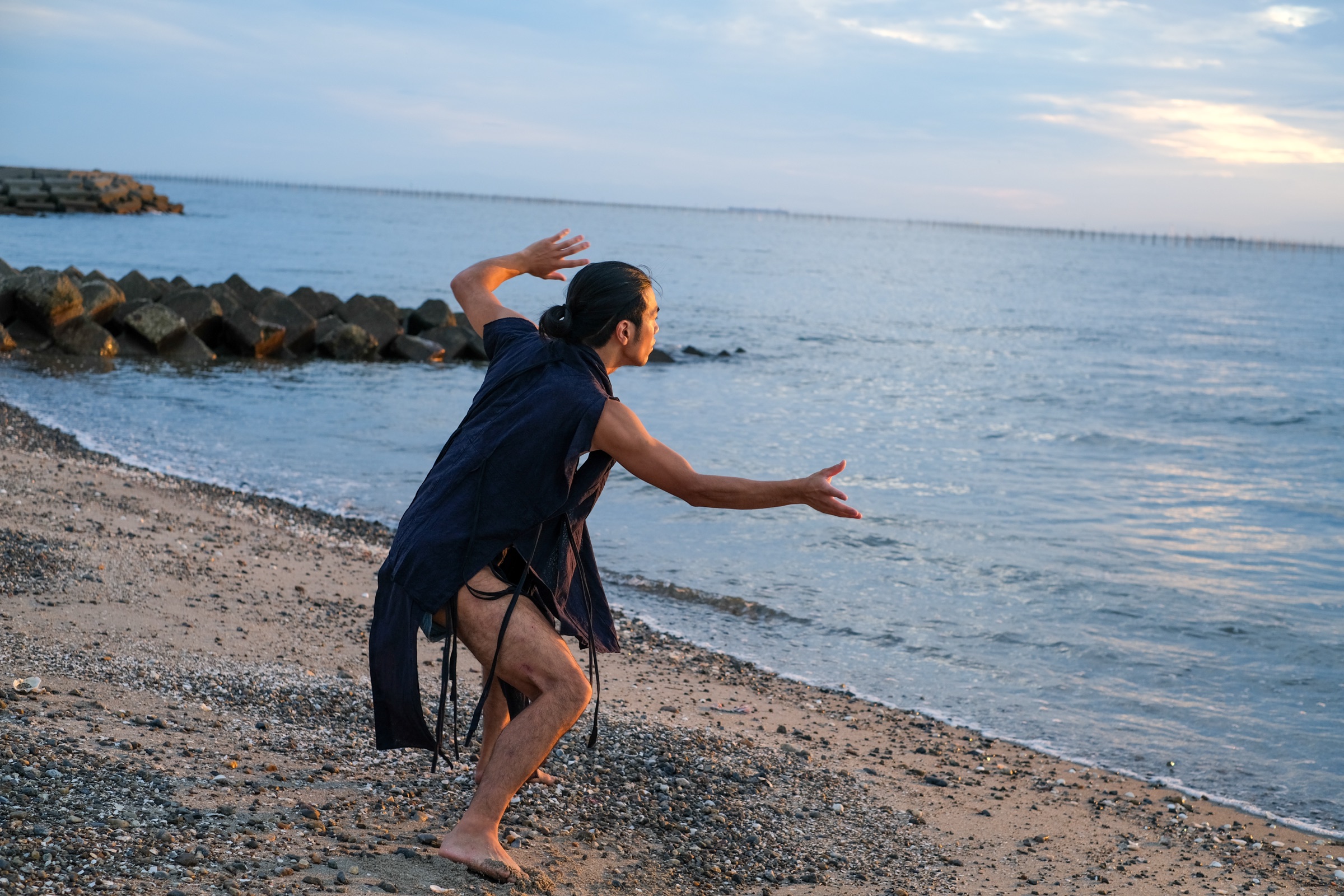 夕暮れの海辺で動きを続けるMIKAGE 三影